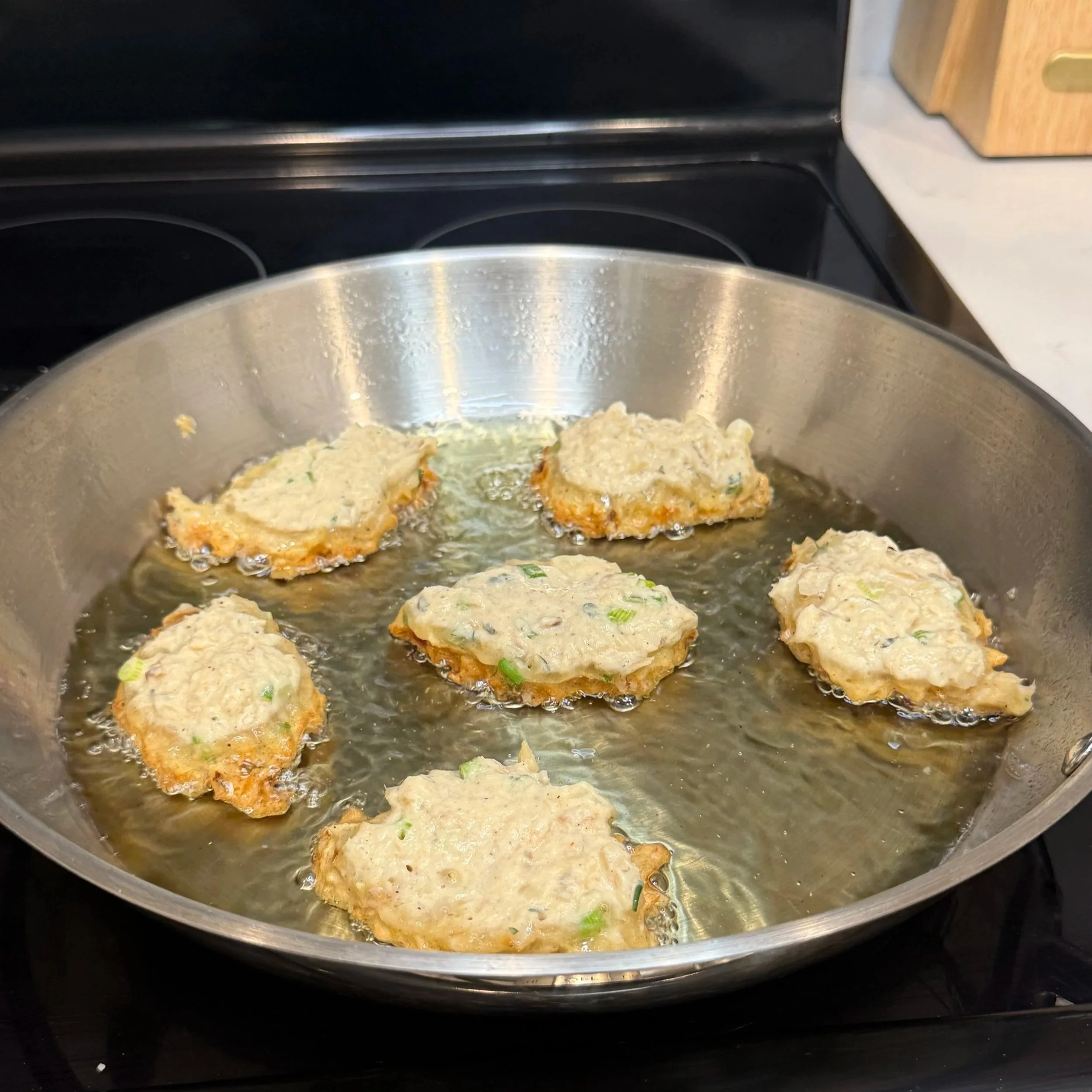 Fritters frying to a golden brown color as the edges crisp up.