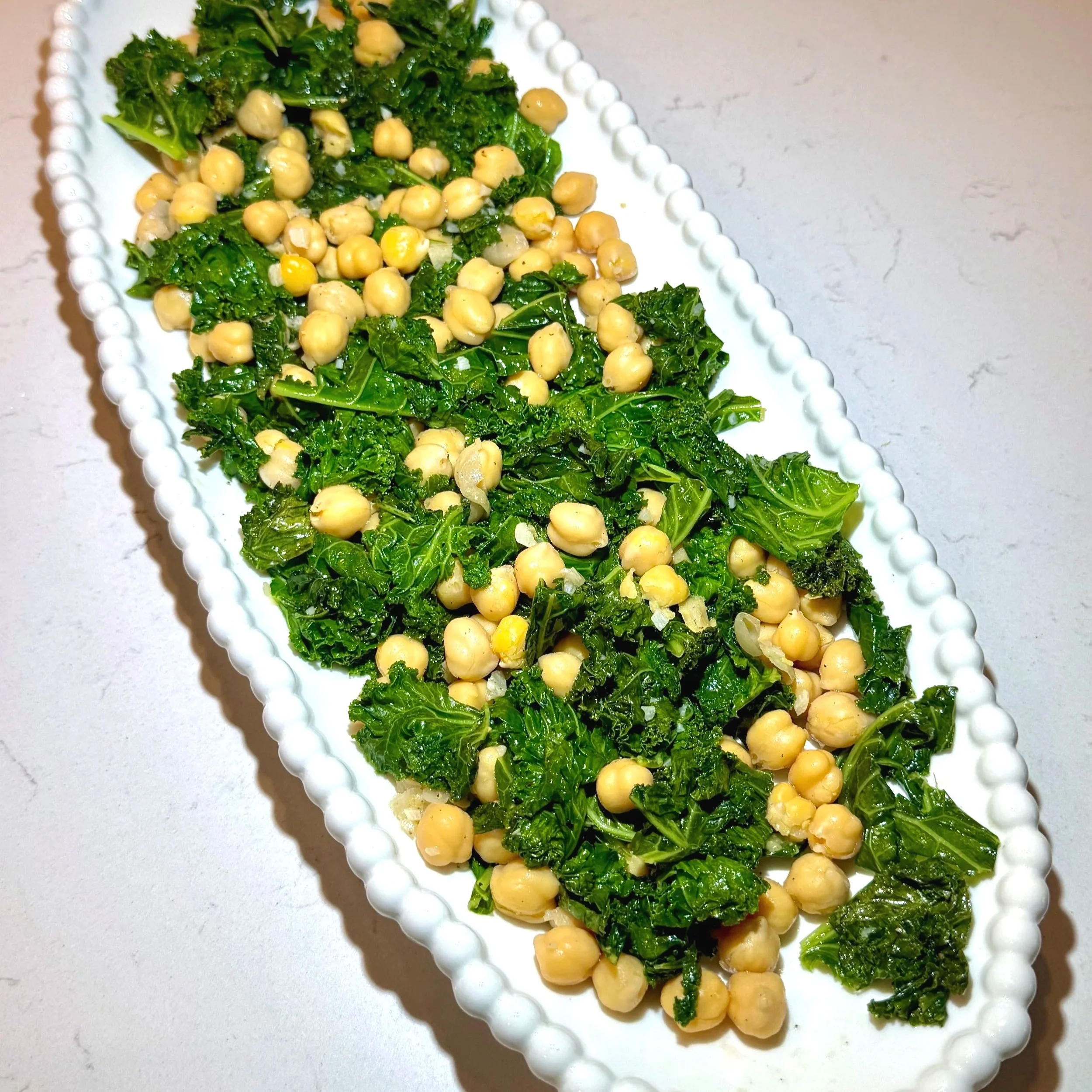 Sauté garlic, kale, and chickpeas until tender — this bright, earthy base balances the richness of the chicken.