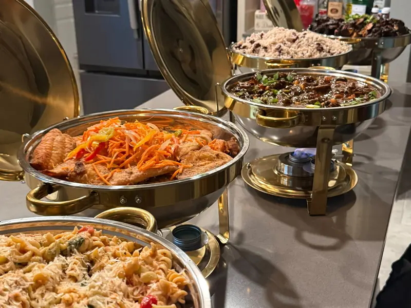 HomeCookVibe Catering buffet in gold chafing dishes with escovitch fish, oxtail, rice and peas and pasta