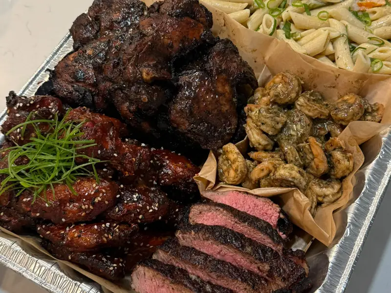 HomeCookVibe Signature Catering Pan with jerk chicken thighs, glazed wings, garlic butter shrimp, sliced pimento-crusted steak and Rasta pasta
